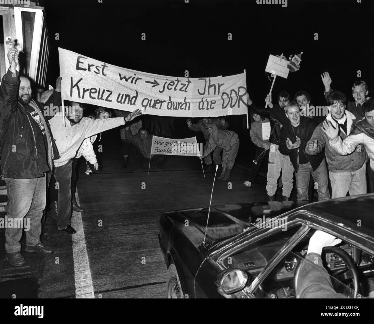 (Afp) - Des fichiers autour de 1.000 citoyens de la RDA accueillent les visiteurs de l'Allemagne de l'Ouest avec une affiche "wir jetzt Erst, Ihr - Kreuz und quer durch die DDR' (Lit. "Nous avons d'abord, maintenant vous - dans toute la RDA) à la sortie d'autoroute la plus Gudow-Zarrentin point de passage en Allemagne, le 24 décembre 1989. De nombreux citoyens de l'Allemagne de l'Ouest retour payé visites à des parents et amis de l'Allemagne de l'Est après l'ouverture partielle Banque D'Images