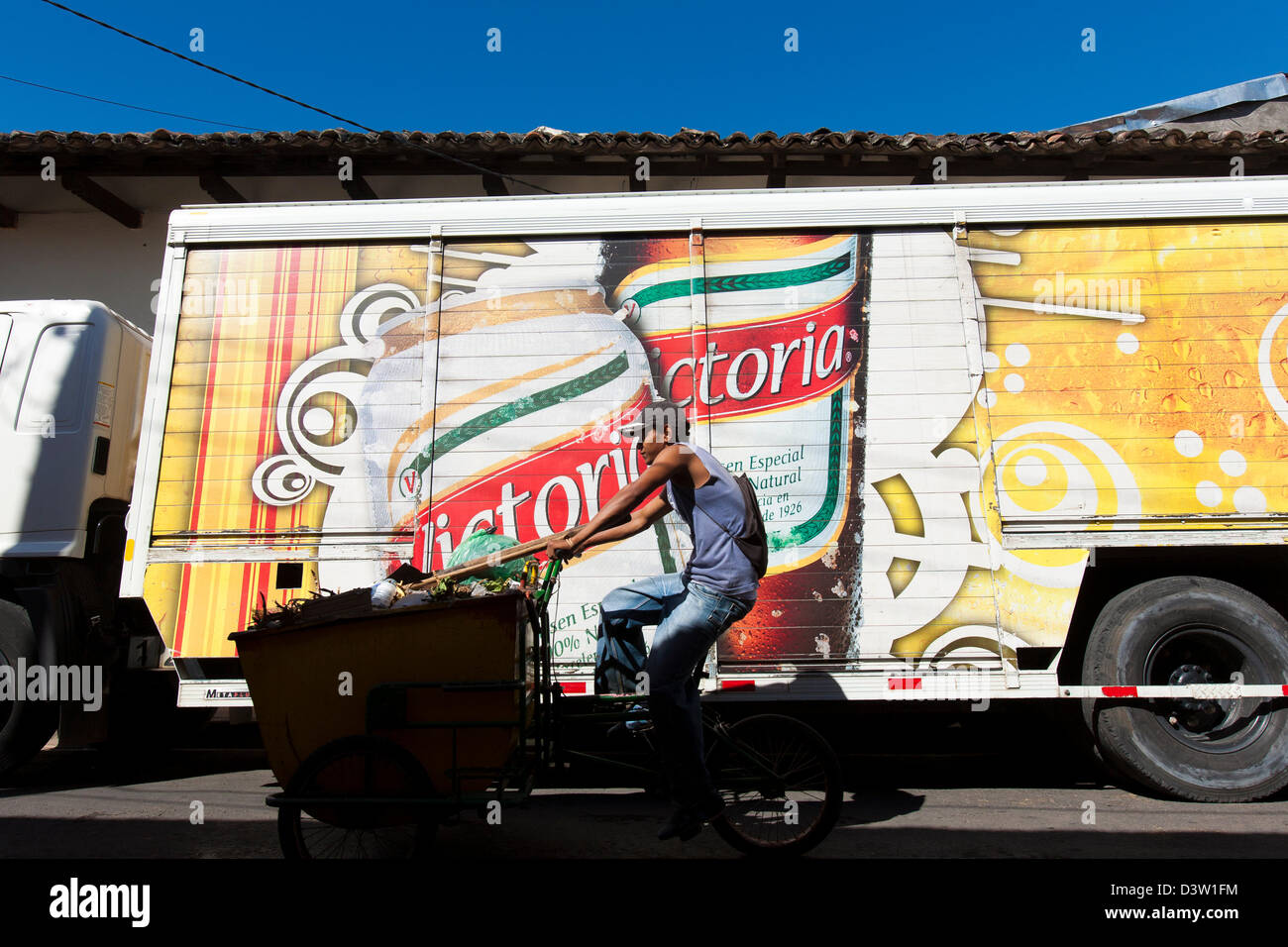 Un homme cours des cycles des camions de livraison de bière à Grenade avec des autocollants et logos pour la bière Victoria, un populaire cerveza au Nicaragua Banque D'Images