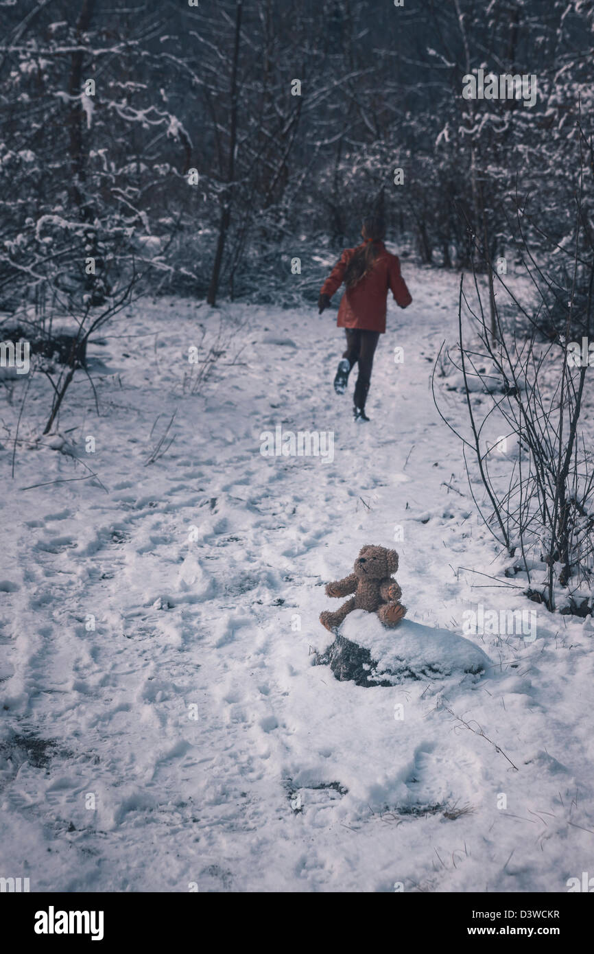 Un ours est assis dans la neige, une fille se sauve Banque D'Images