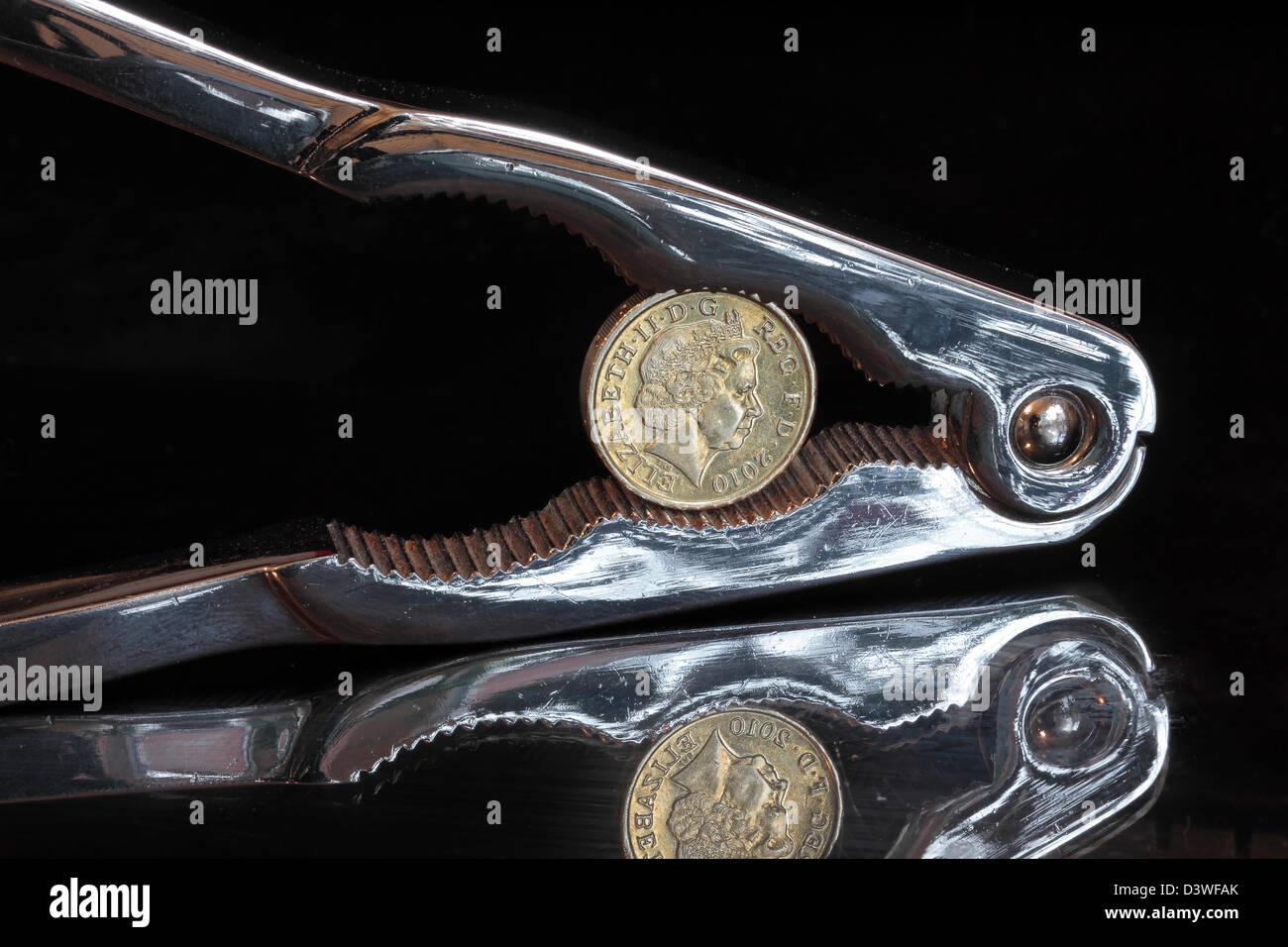 Pound coins dans Nut Cracker sur fond sombre reflet Banque D'Images