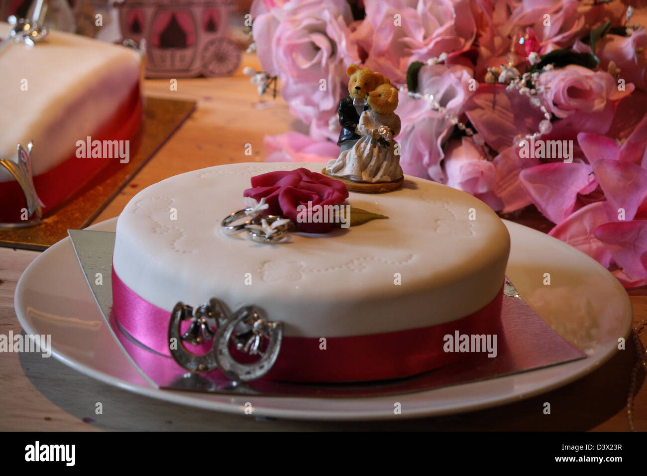 Gâteau de mariage avec deux ours sur elle avec un bouquet de fleurs derrière. Banque D'Images