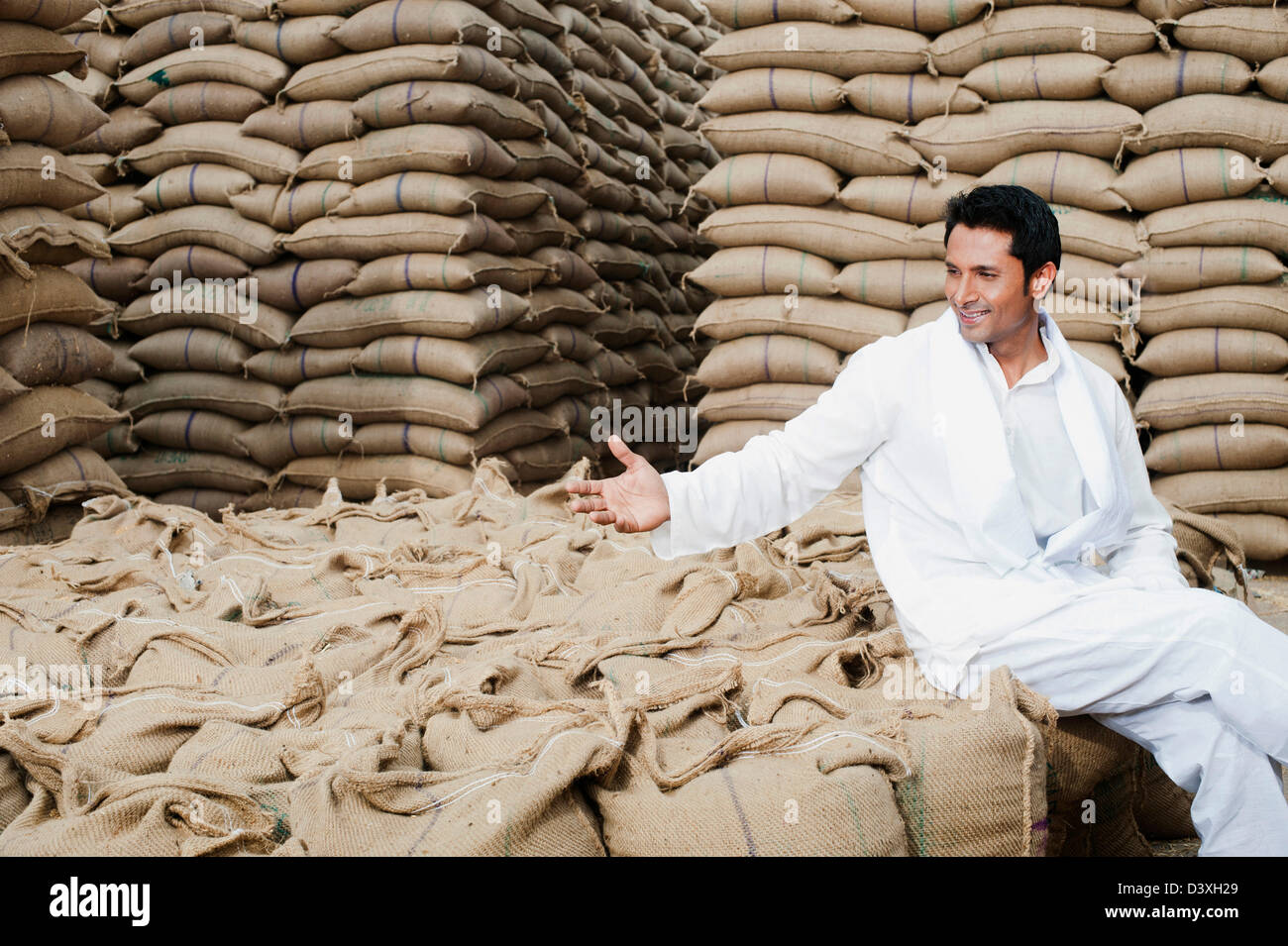 Homme assis sur le sac de blé Céréales, Anaj, Mandi, Sohna Gurgaon, Haryana, Inde Banque D'Images