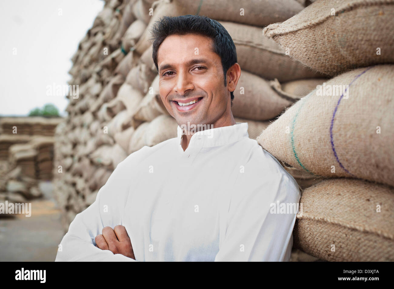 L'homme appuyé contre une pile de sacs de blé, Anaj, Mandi, Sohna Gurgaon, Haryana, Inde Banque D'Images