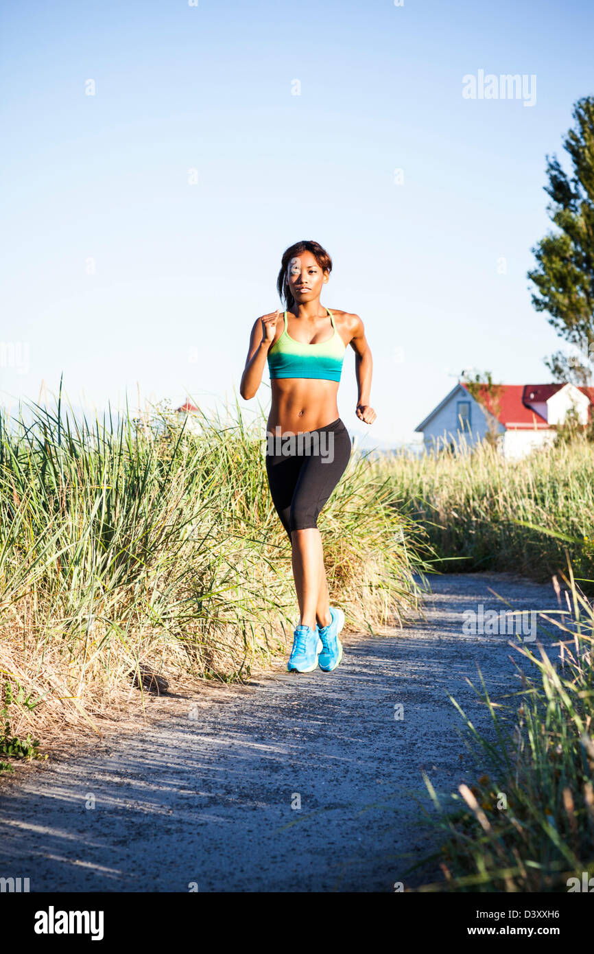 Mixed Race woman running on beach Banque D'Images