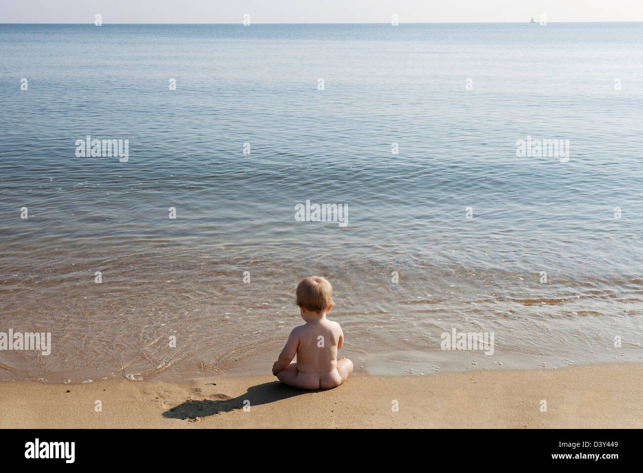 Caucasian baby sitting on beach Banque D'Images