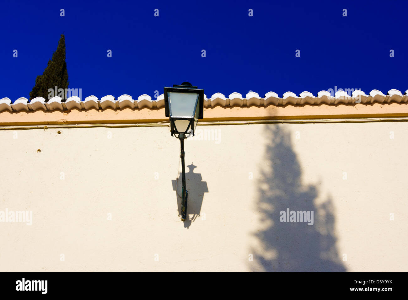 Mur blanchis d'un Carmen maison avec lampe de rue, cyprès et d'ombre à une petite ruelle typique de Grenade, Andalousie, Espagne Banque D'Images