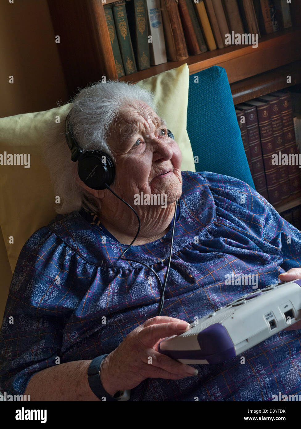 Vieille dame âgée isolant covid-19 CORONAVIRUS écoutant le livre audio, avec un lecteur de CD à utiliser par les personnes malentendantes, malvoyantes Banque D'Images