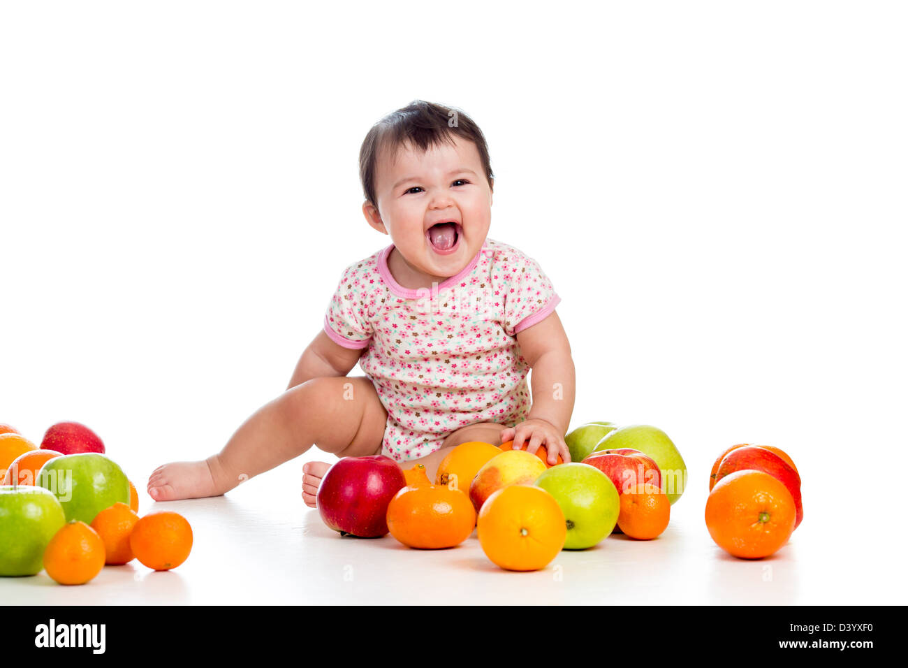 Happy baby girl sitting parmi les fruits frais Banque D'Images