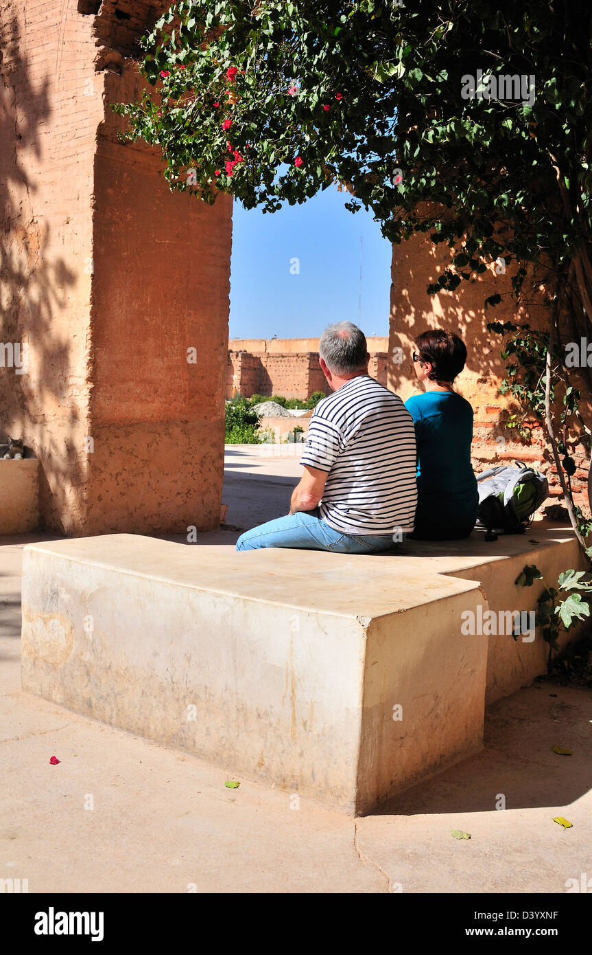 Les touristes, hommes et femmes, vue arrière, de repos et d'assise sous arbre dans le parc du palais El Badii, Marrakech, Maroc Banque D'Images