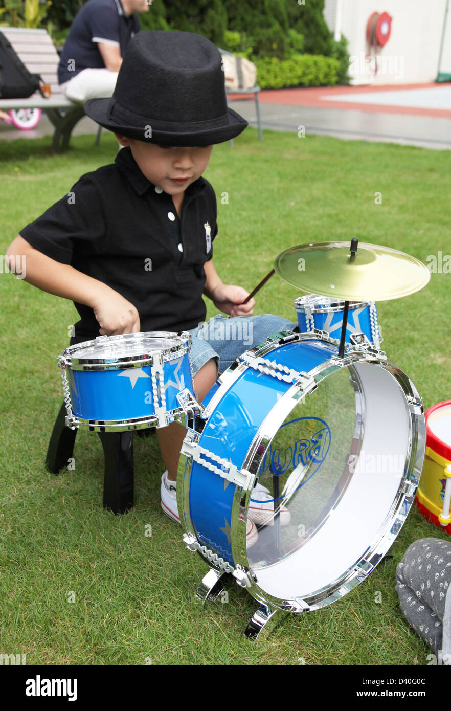 C'est une photo d'un jeune enfant garçon qui joue de la batterie sur un jouet  enfant instrument musique batterie. C'est en bleu et sur l'herbe Photo  Stock - Alamy