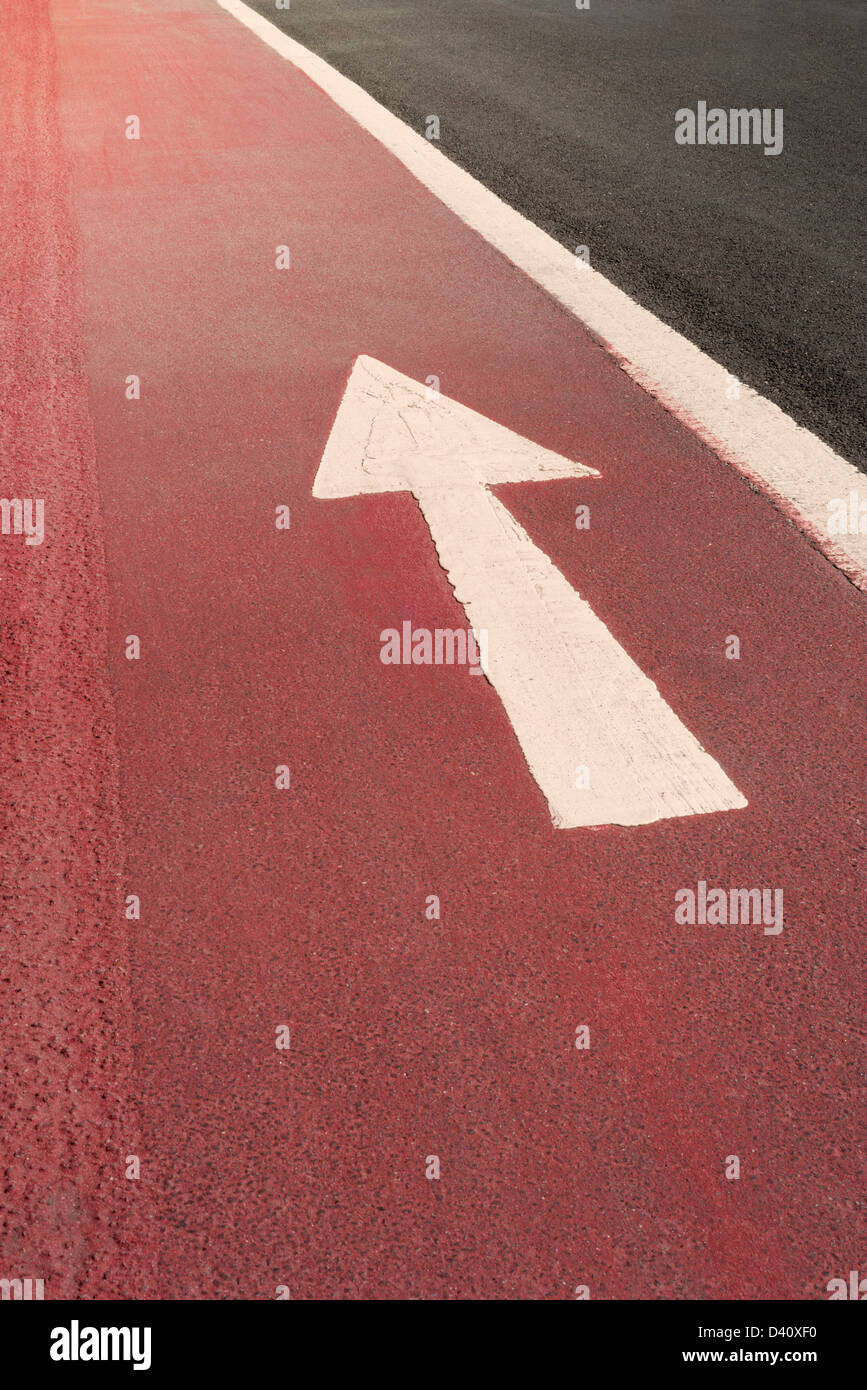White tout droit d'une façon flèche de direction le marquage routier peint sur une surface rouge, UK Banque D'Images