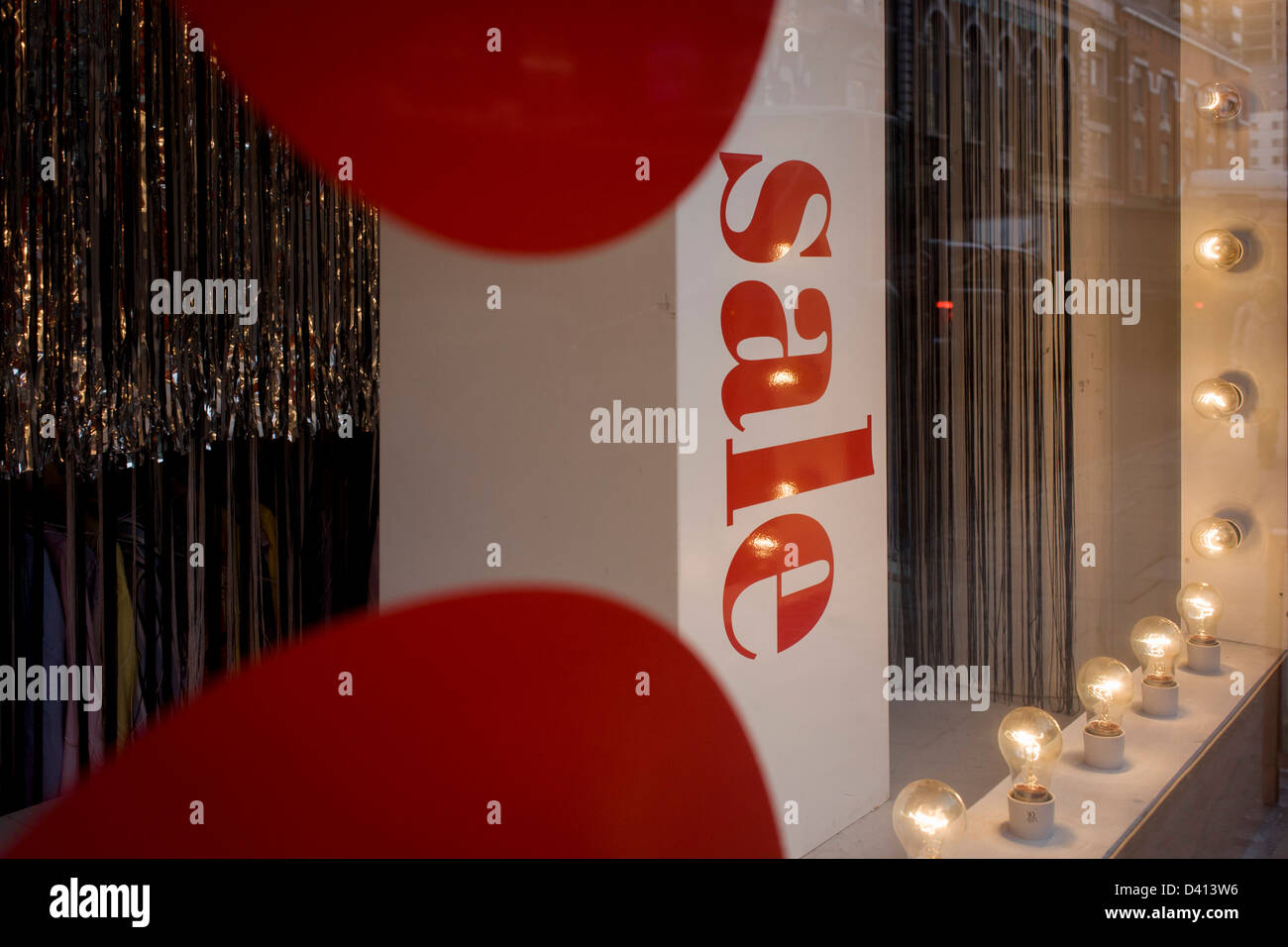 Une vente est considérée signe entouré par un thème rouge et les ampoules dans la fenêtre d'une rue du centre de Londres. Banque D'Images