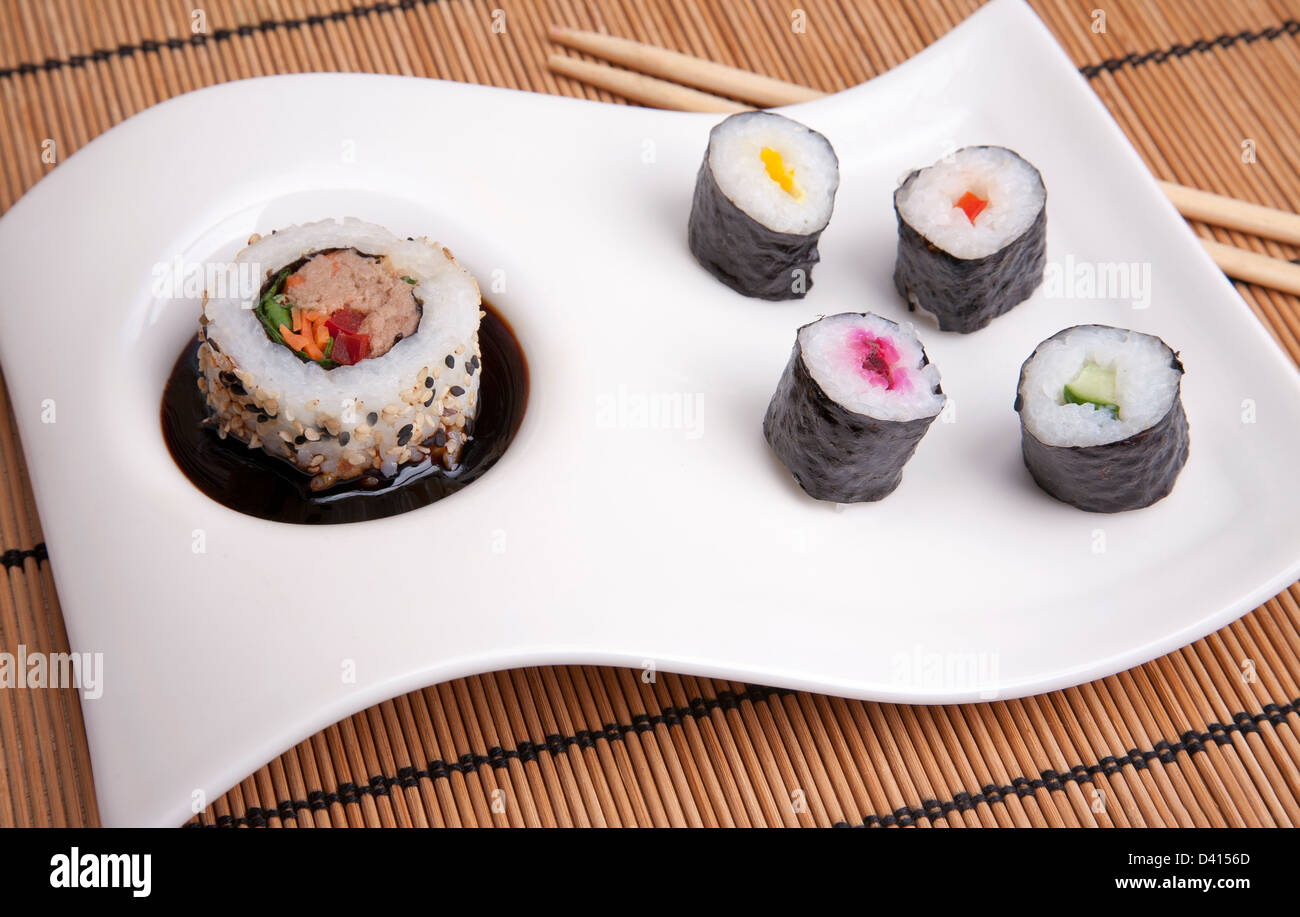 Sushi on a plaqués platine avec riz légumes pêcher le thon au chop stix sur un tapis de bambou Banque D'Images