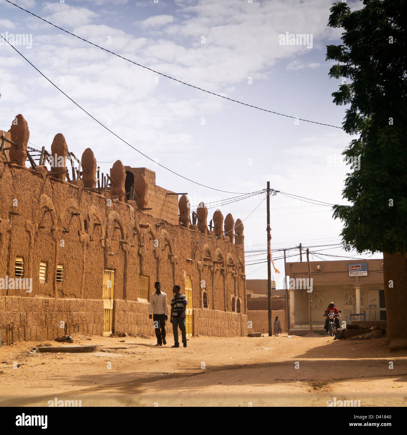 Les hommes passent devant un bâtiment traditionnel à Agadez Banque D'Images