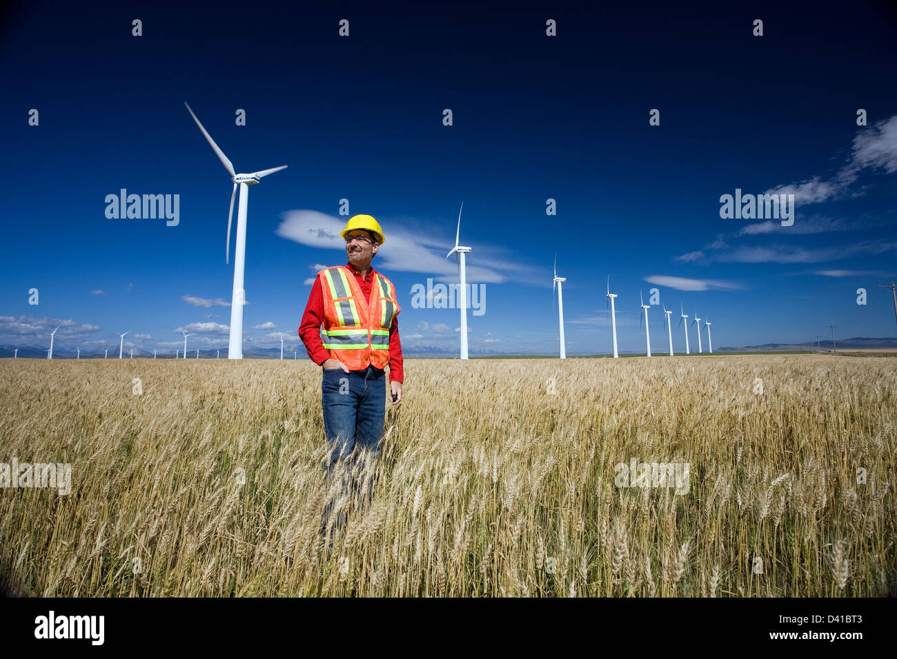 Technicien en énergie éolienne debout à côté d'éolienne, près de Pincher Creek, en Alberta. Banque D'Images