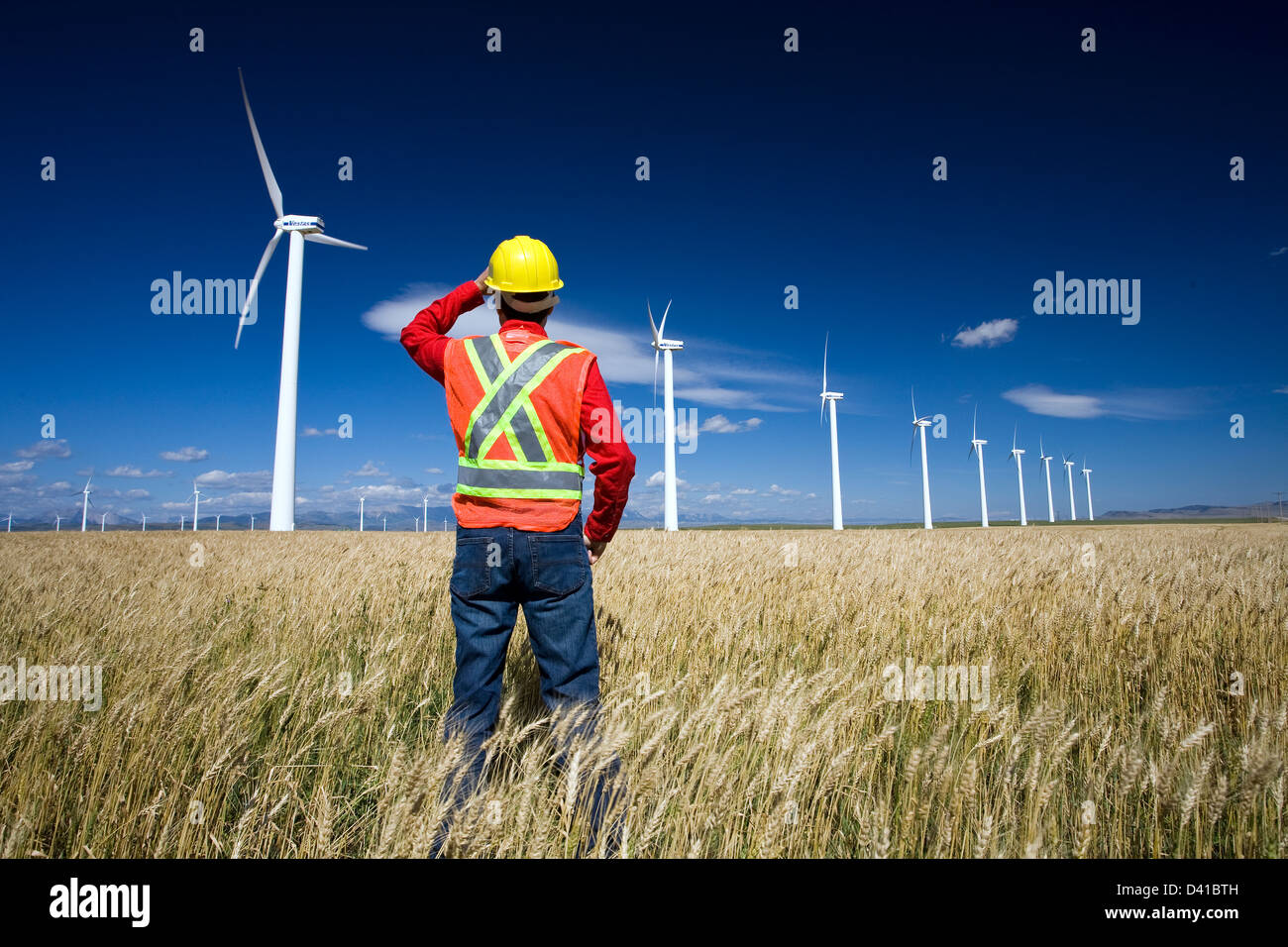 Technicien en énergie éolienne debout à côté d'éolienne, près de Pincher Creek, en Alberta. Banque D'Images