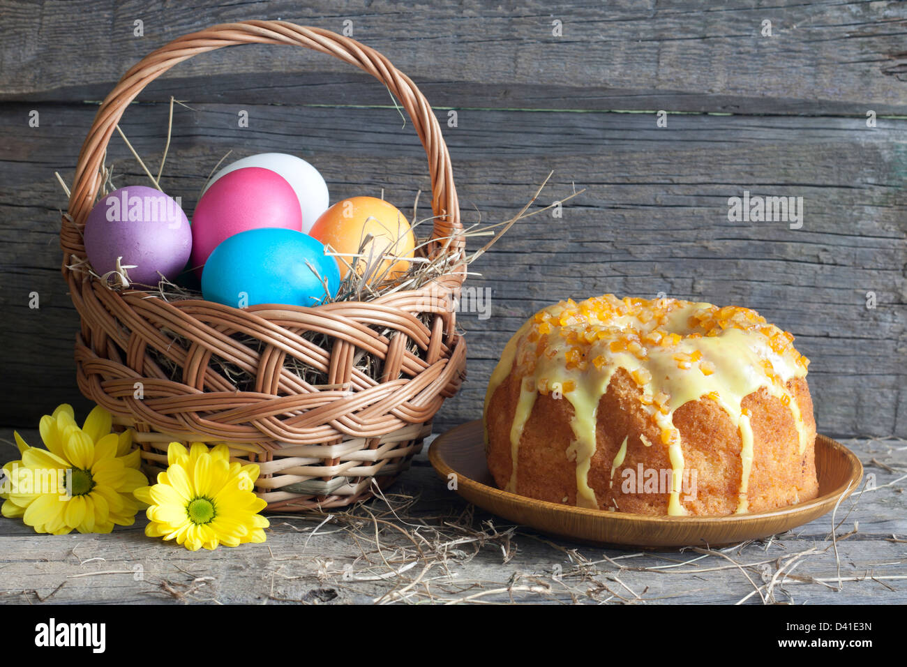 Oeufs de Pâques dans le panier et le gâteau sur une table en bois vintage Banque D'Images