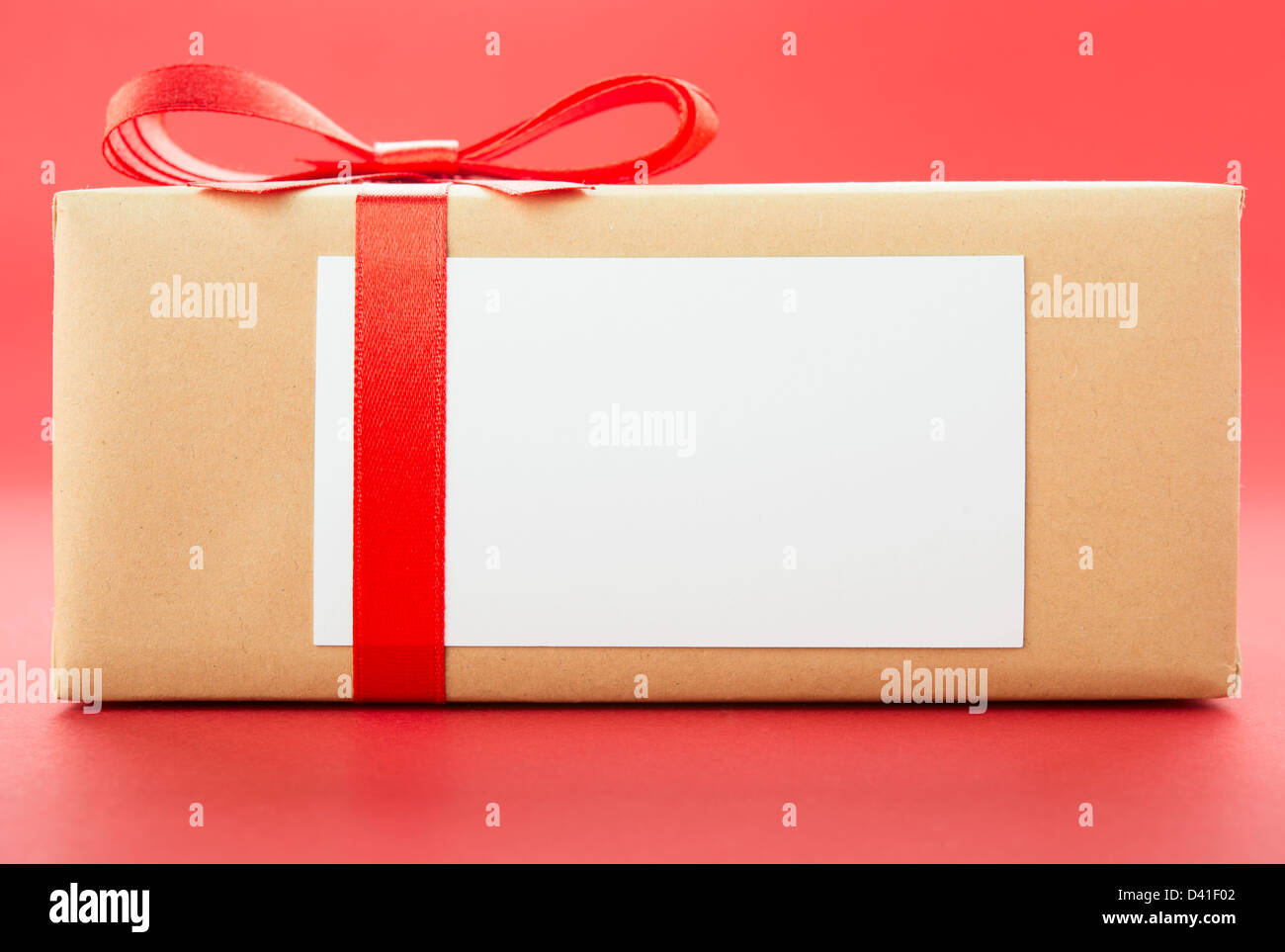 Boîte cadeau enveloppé avec red bow, isolé sur fond rouge Banque D'Images
