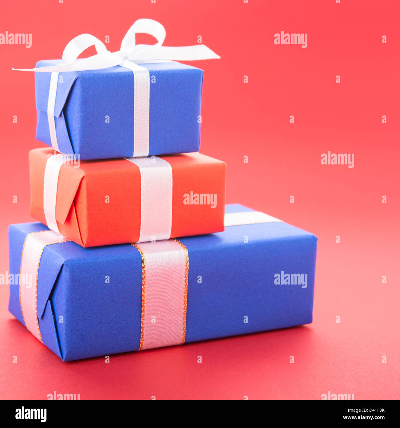 Boîtes cadeaux avec un arc, isolé sur fond rouge Banque D'Images