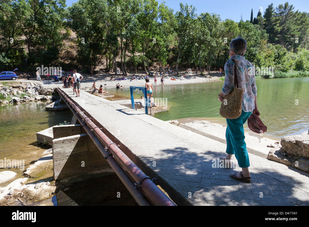 Une touriste traverse un pont sur la rivière de l'orbieu à Lagrasse, Languedoc, France. Banque D'Images