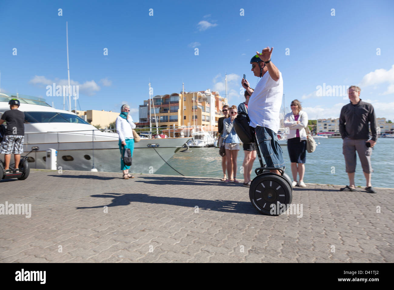 Un touriste explore la marina à Gruissan, France sur son segway, embauchés pendant l'utilisation de son téléphone portable à la vidéo de l'événement. Banque D'Images