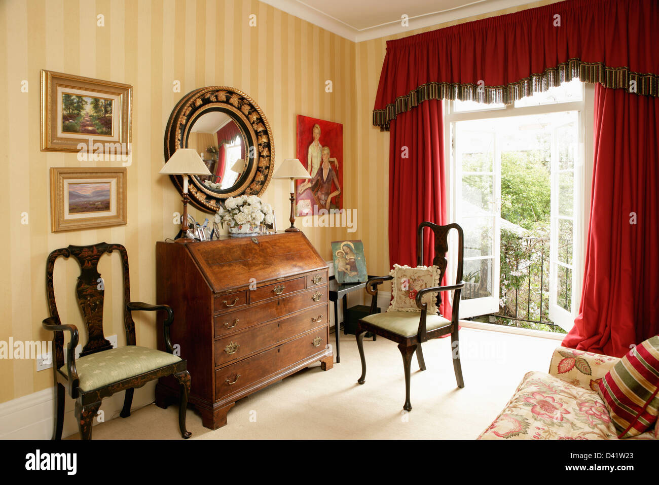 Bureau antique et des chaises confortables en étude maison avec des rideaux en velours rouge sur windows en français Banque D'Images