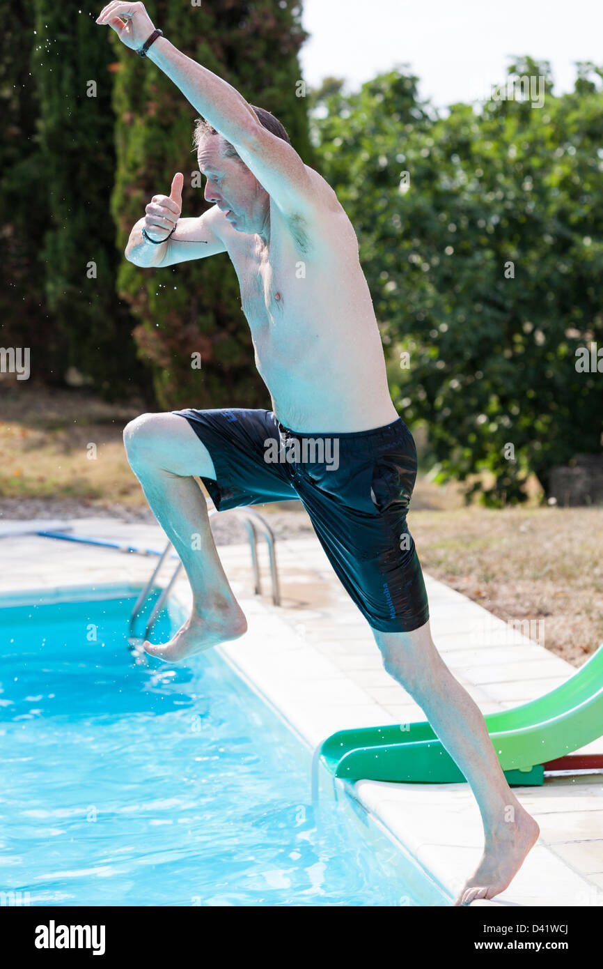 L'homme 'Superman' adopte une pose comme il saute dans une piscine Photo  Stock - Alamy