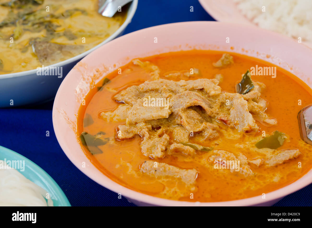 La viande de porc au rez-de-arachide la crème de coco et curry aliments différents sur tableau bleu Banque D'Images