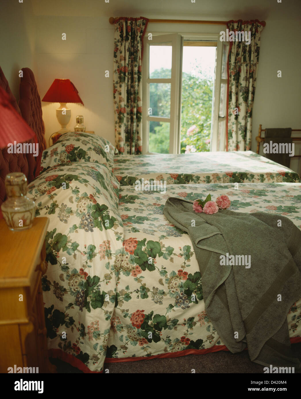 Drap de bain gris sur lit avec lit floral-couverture en anglais pays  chambre avec lits jumeaux et une fenêtre avec des rideaux Photo Stock -  Alamy