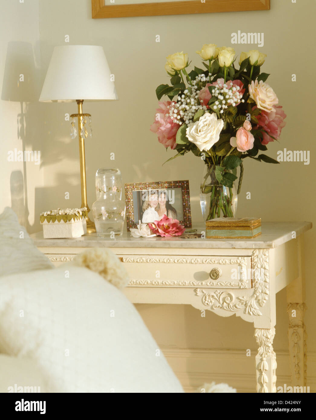Lampe blanche et l'été des fleurs dans vase en verre recouvert de marbre sur table crème au coin de chambre Banque D'Images