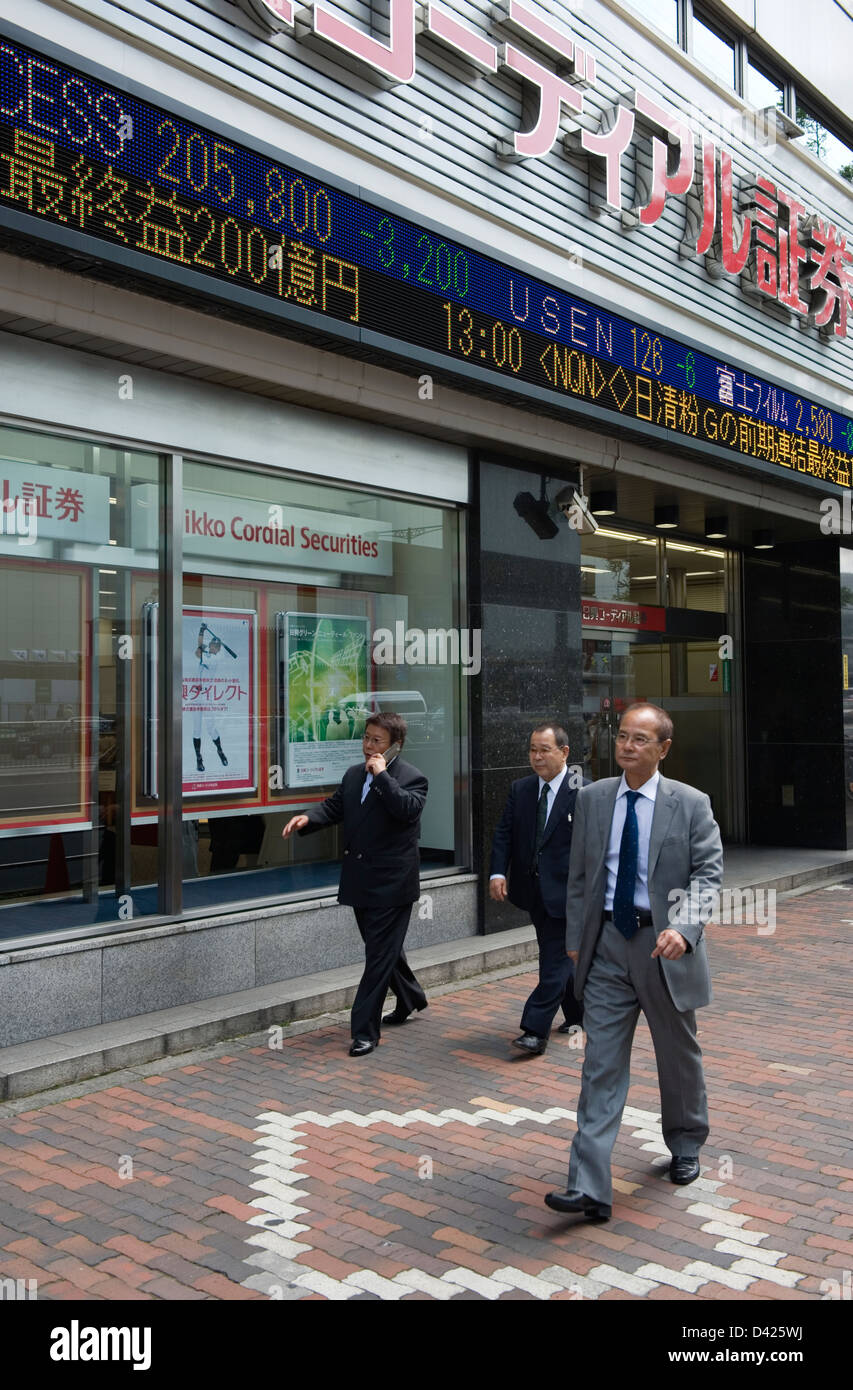 Les hommes d'affaires et les piétons en passant devant la bourse électronique de serpentins à société de valeurs mobilières dans le centre-ville de Tokyo, au Japon. Banque D'Images