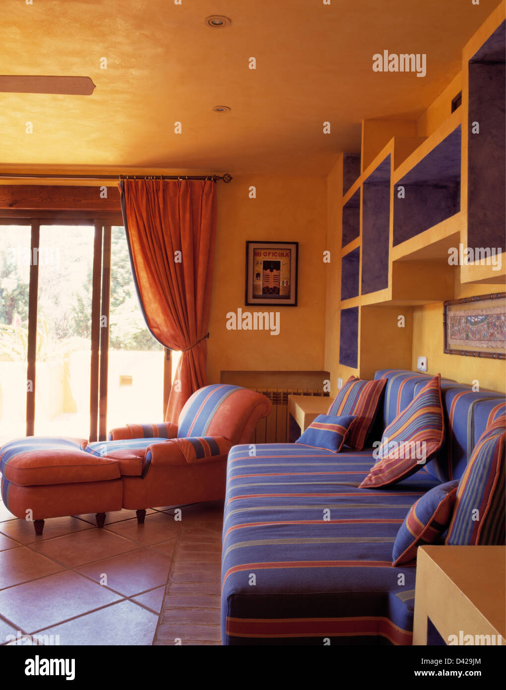 Rayé rose +bleu canapé et fauteuil rose avec des selles dans un salon jaune  moderne avec sol en espagnol villa Photo Stock - Alamy