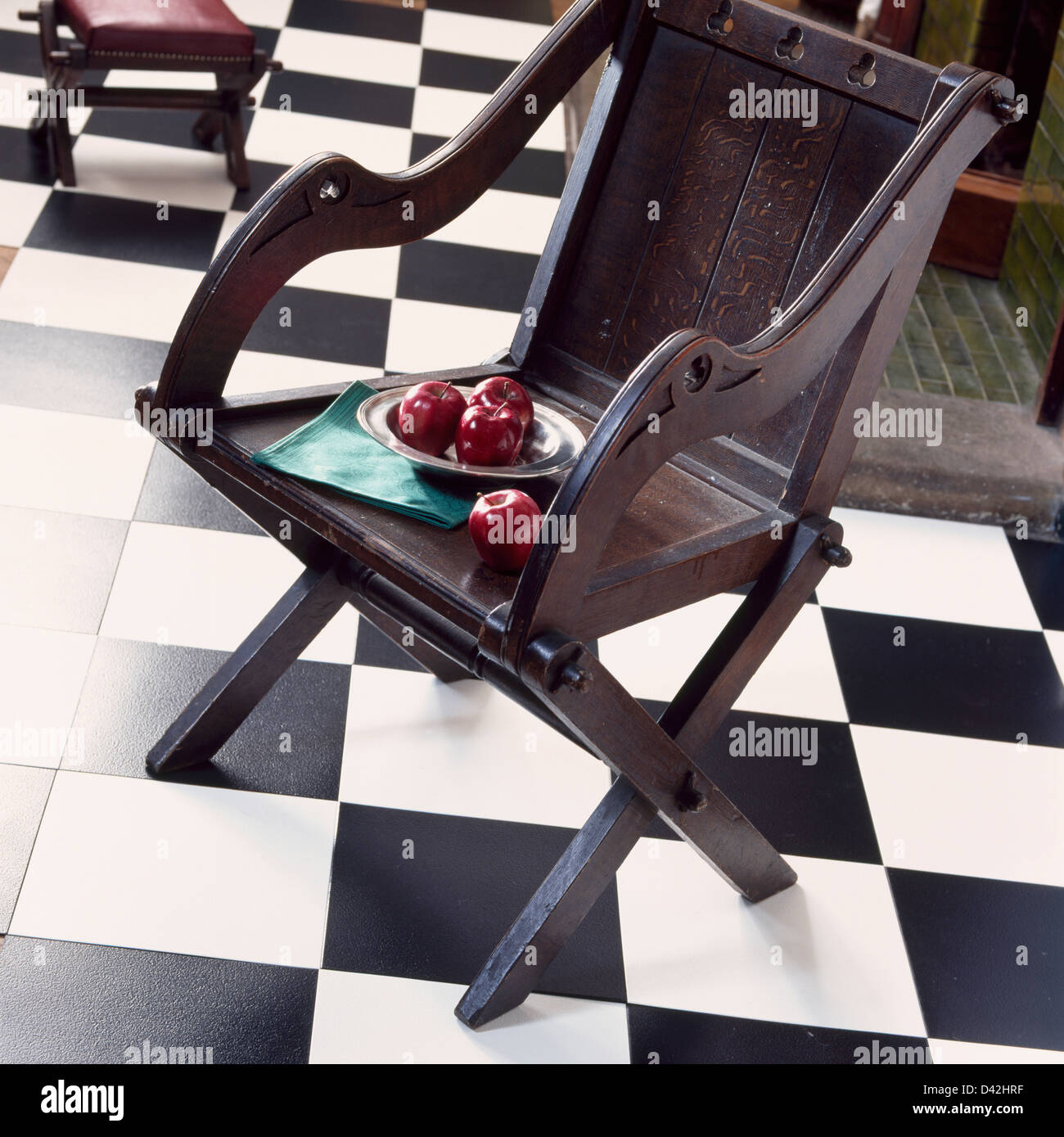 Des pommes rouges sur la plaque en bois chaise sur noir +vinyle blanc sol en damier Banque D'Images