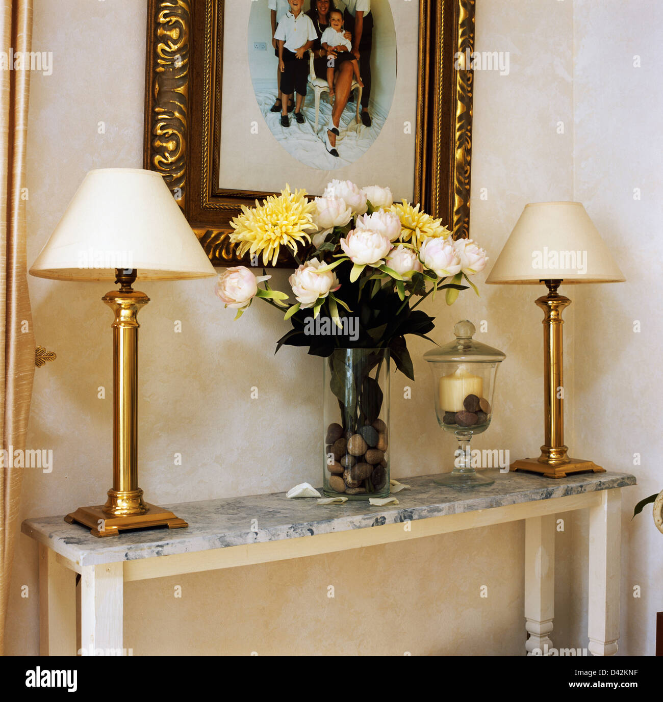 Lampes dorées avec des tons crème recouvert de marbre sur table console avec vase de roses crème et jaune pâle chrysanthèmes Banque D'Images