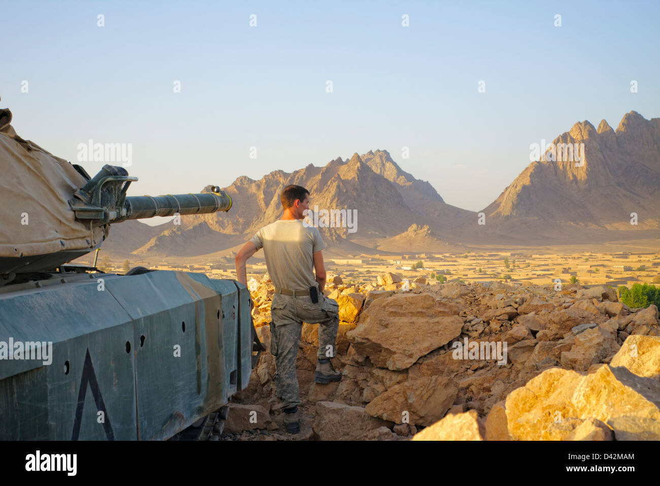 Au sommet d'une position défensive, un soldat donne sur un village de la province de Kandahar, Afghanistan. Banque D'Images