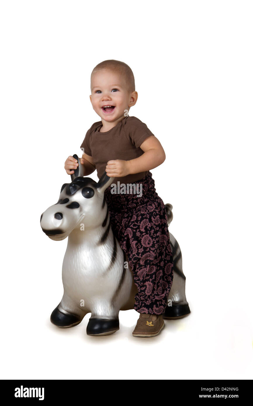 Heureux l'enfant (1,5 ans) à cheval sur un cheval gonflable sur un fond blanc Banque D'Images