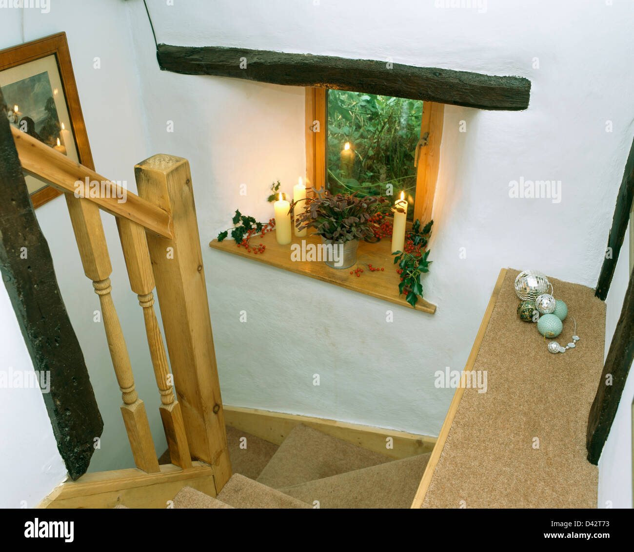 À la maison vers le bas des escaliers pour des bougies allumées sur les petits, fenêtre encastrée avec décorations de Noël feuillage Banque D'Images