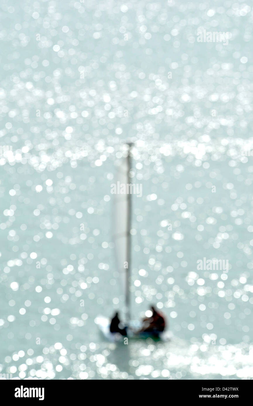 Image floue d'un petit voilier à la lumière scintille Banque D'Images