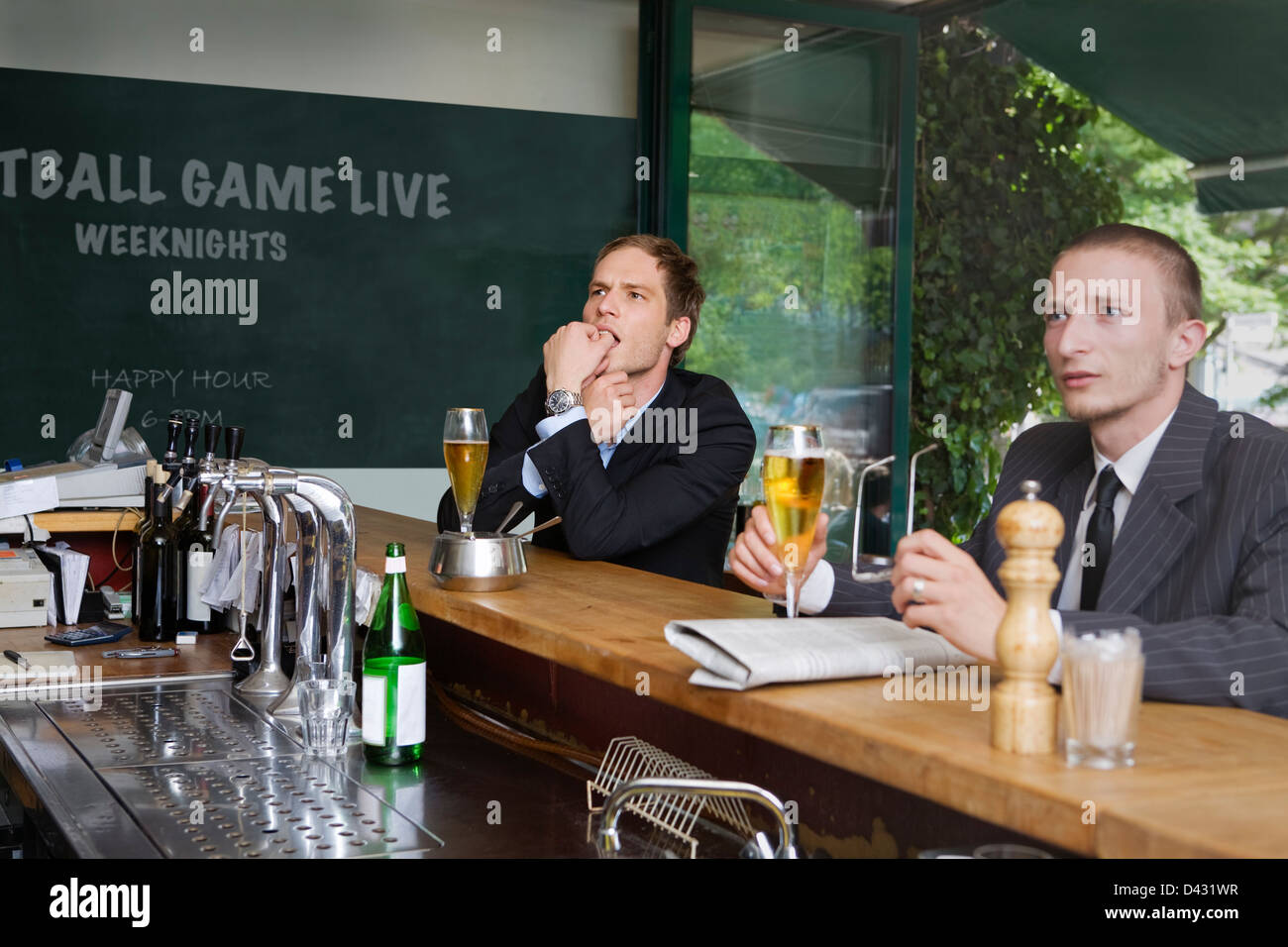 Deux hommes d'affaires de près l'évolution d'un jeu télévisé que dans un bar sportif. Banque D'Images