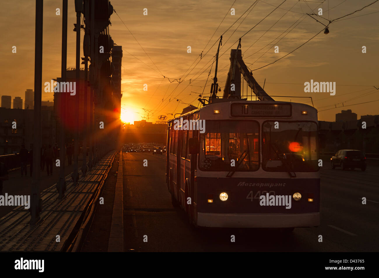 Un trolleybus et des voitures traversant le pont de Crimée à Moscou dans un coucher du soleil la lumière. Banque D'Images