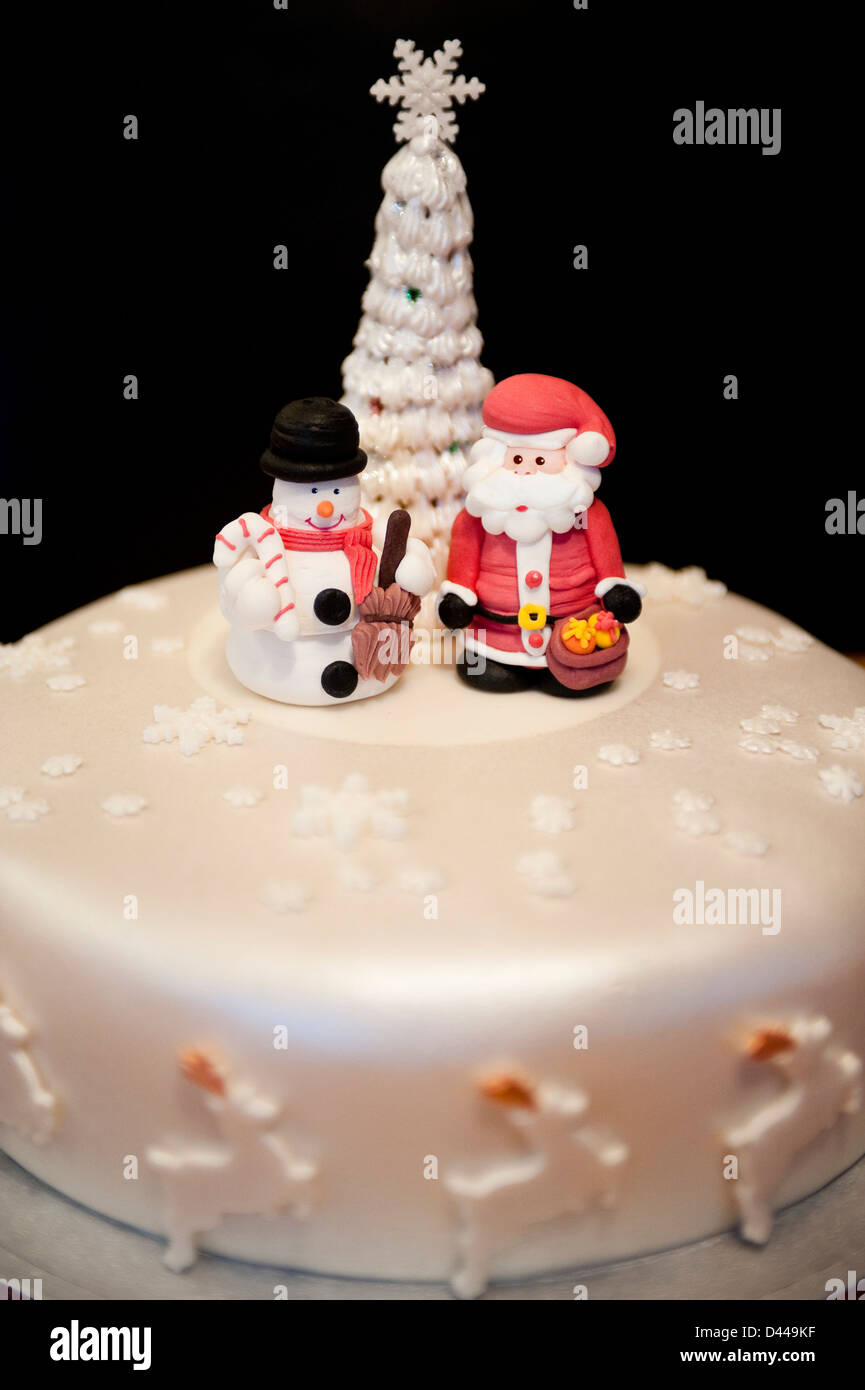 Close up vertical de plaisir modelé les figures de Père Noël et un bonhomme debout sur un gâteau de Noël. Banque D'Images