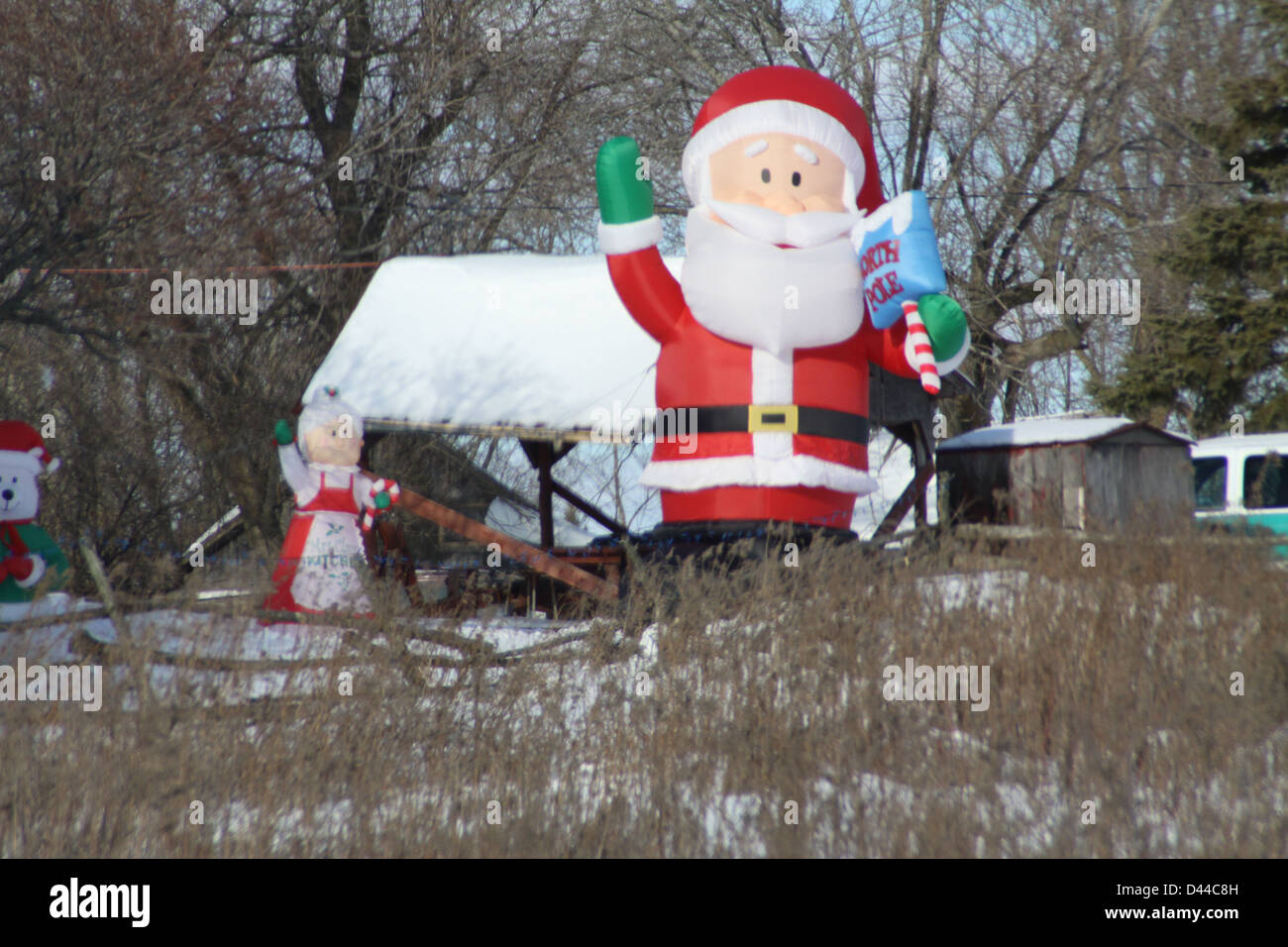 Affichage de triage Blowup Santa Clause dans un champ ouvert avec une couche de neige dans les hautes herbes dans le champ. Banque D'Images