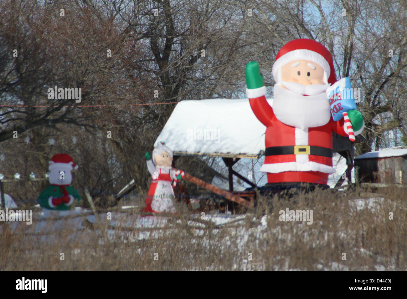 Affichage de triage Blowup Santa Clause dans un champ ouvert avec une couche de neige dans les hautes herbes dans le champ. Banque D'Images