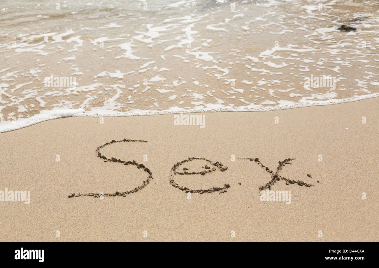 Le mot 'Sex' écrit dans le sable sur une plage tropicale Banque D'Images