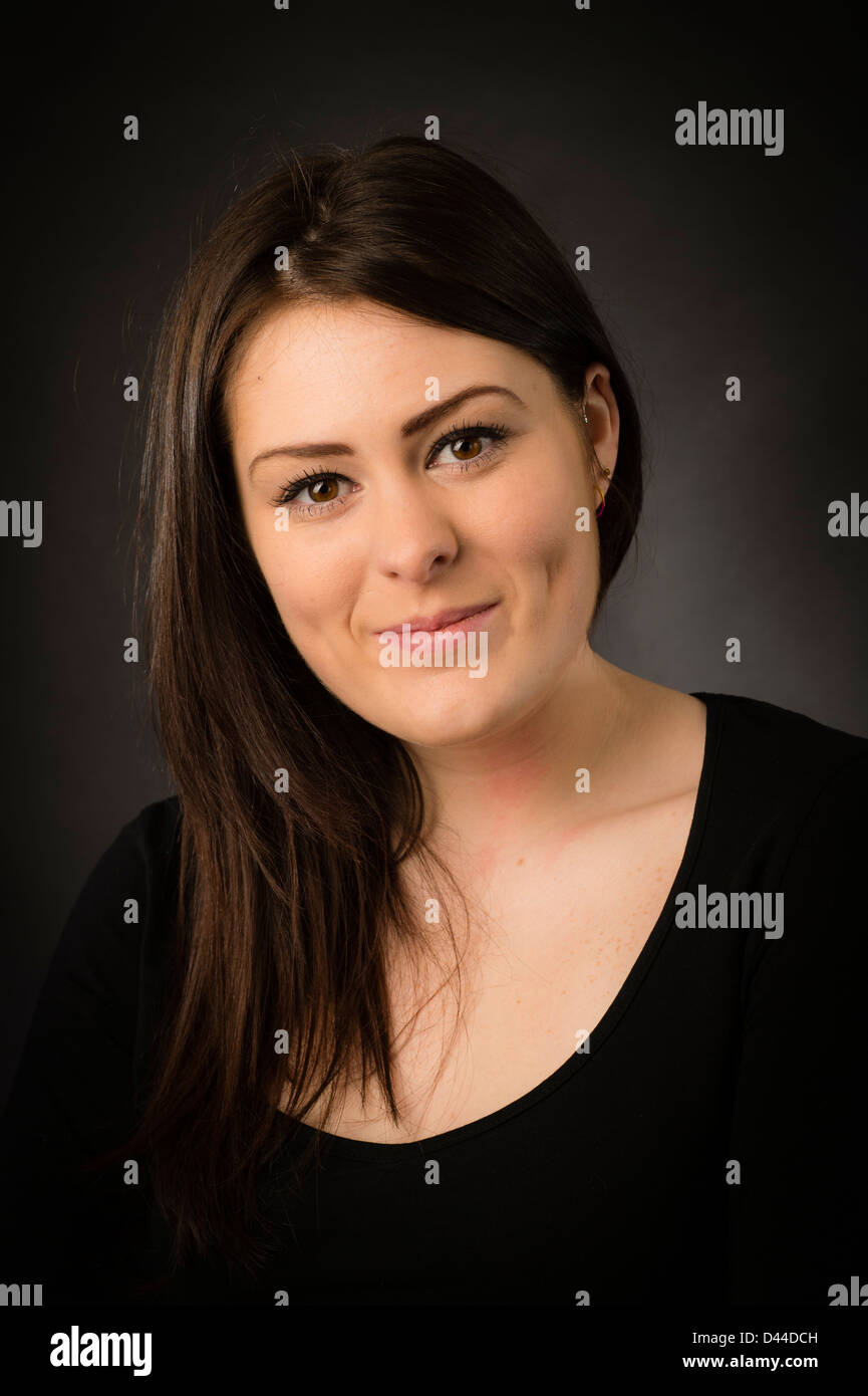 Une jeune fille femme confiant heureux souriant, les cheveux bruns et les yeux, UK Banque D'Images
