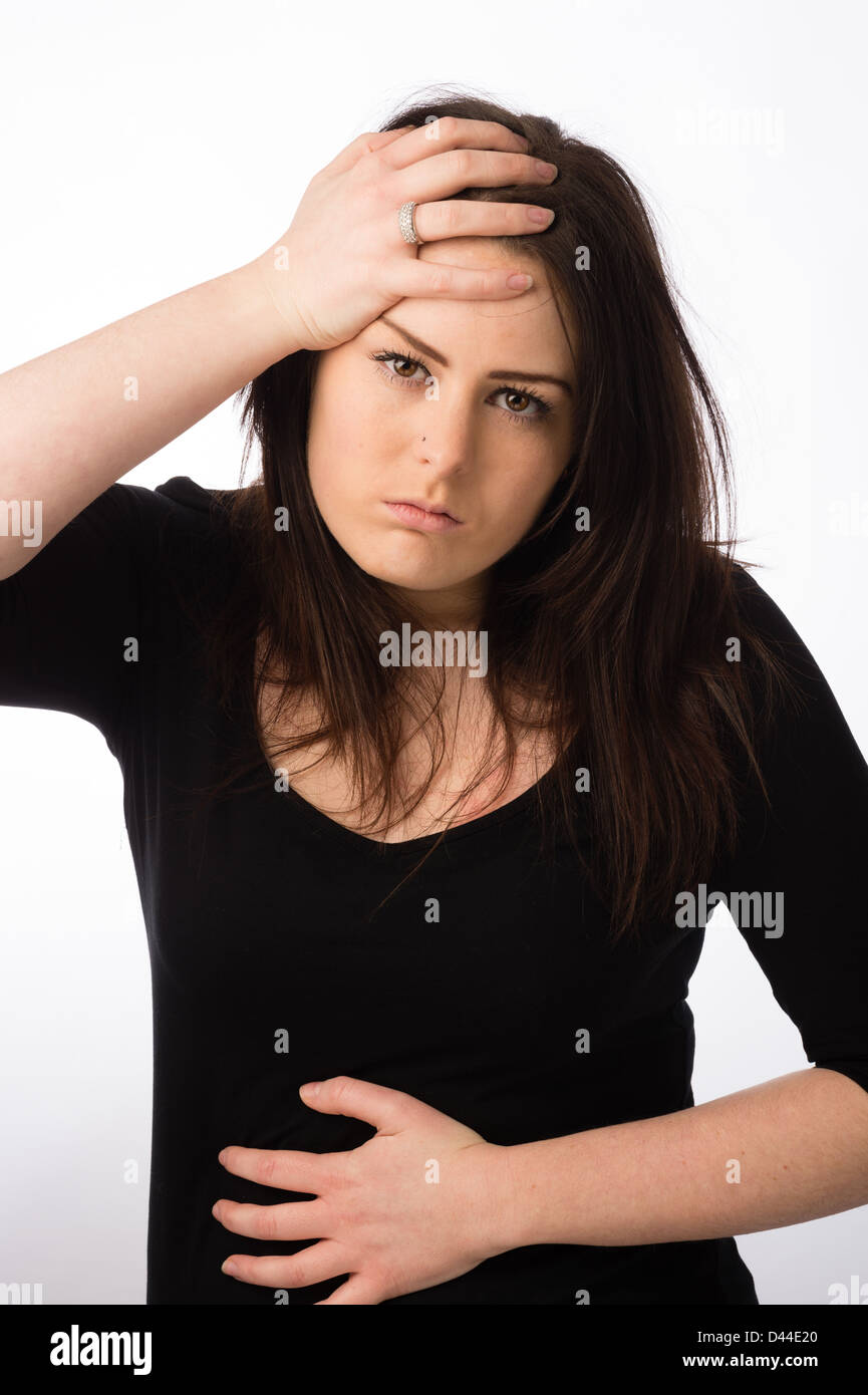 Une jeune femme malade malade malade, les cheveux bruns, main sur son front UK Banque D'Images