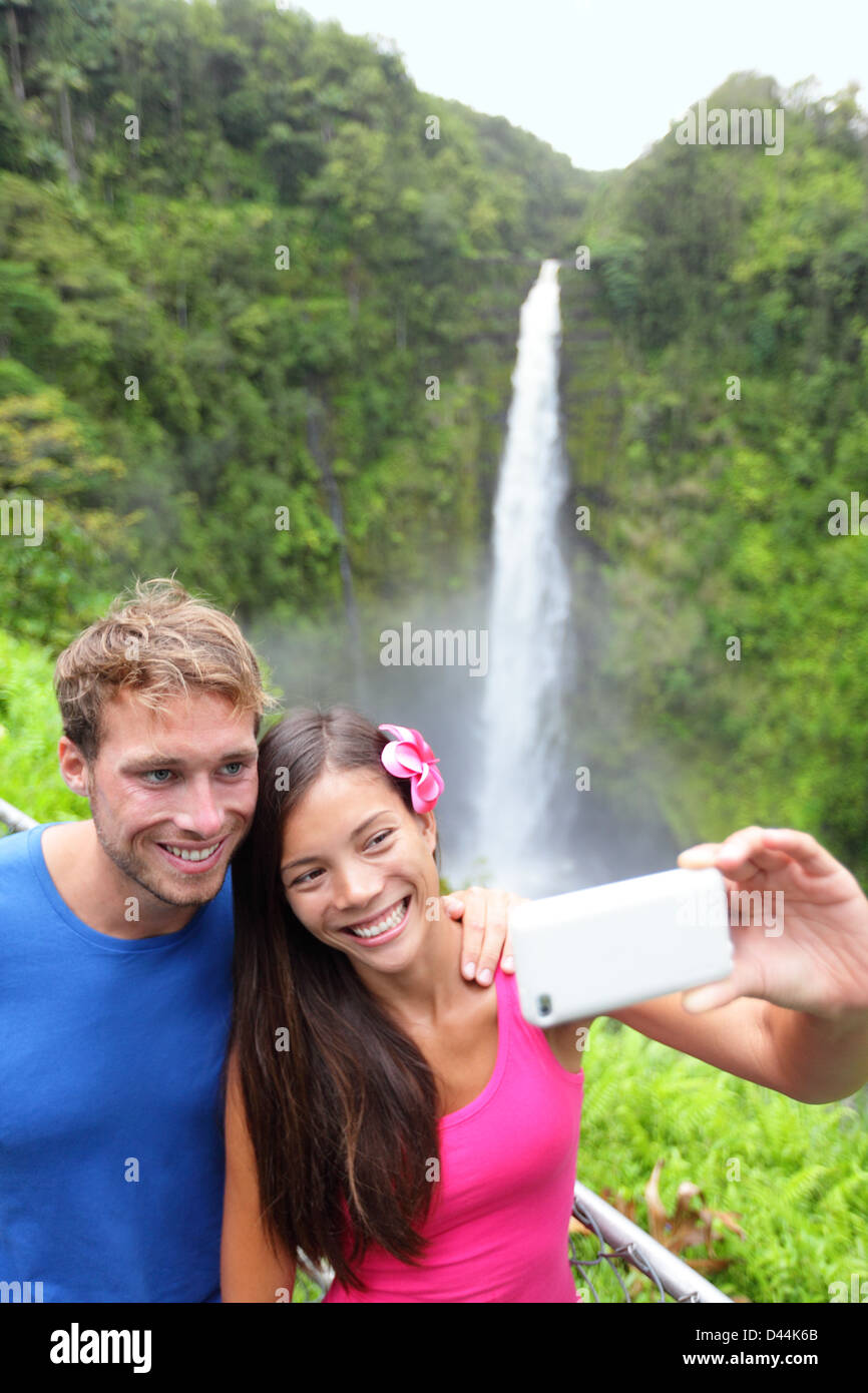 Happy young couple taking self portrait multiethnique photo avec téléphone appareil photo sur Hawaii, grandes îles, Akaka Falls Banque D'Images