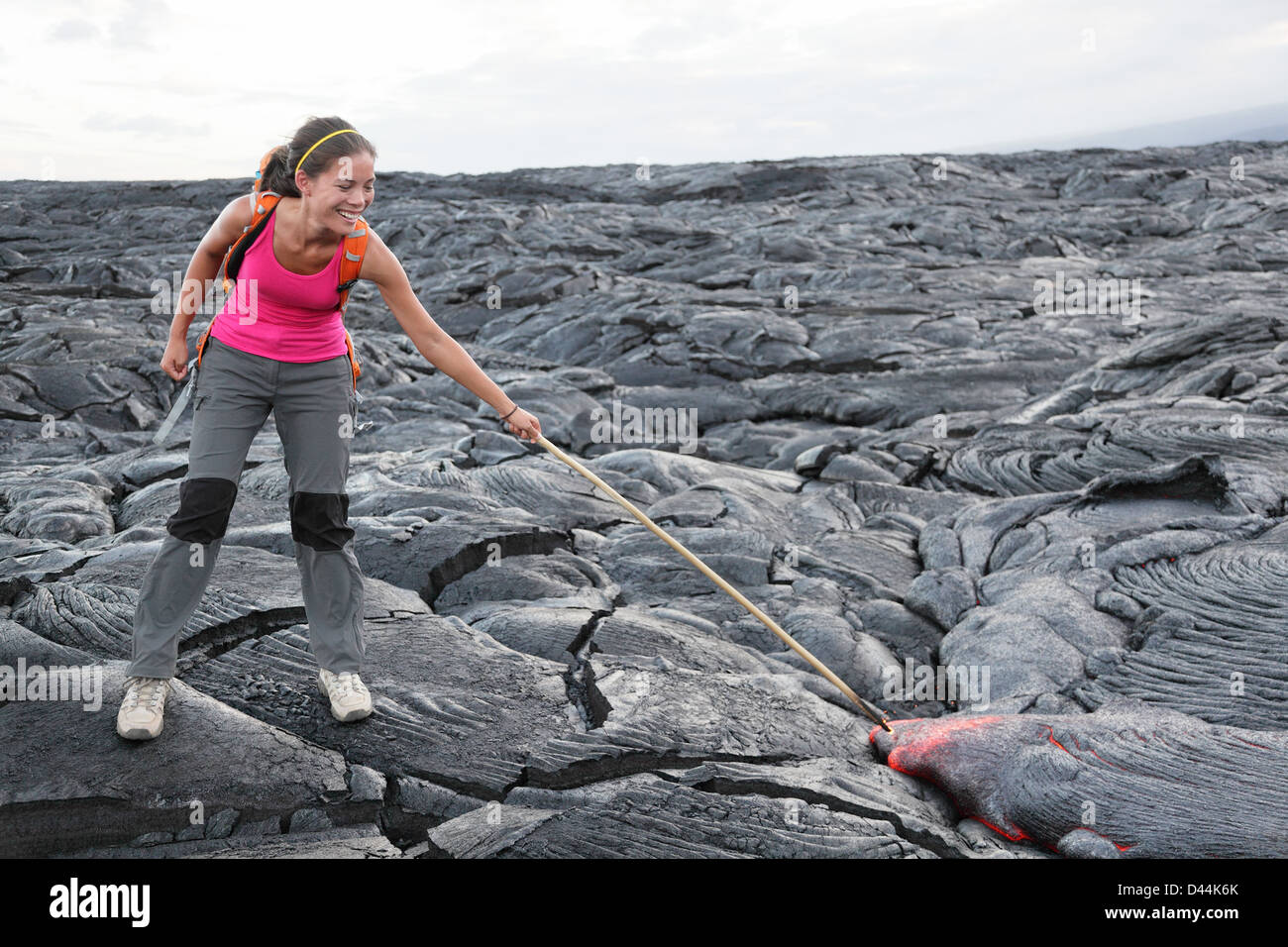 Happy young woman on piquer stick dans red hot gigantesque coulée de lave de volcan Kilauea autour de Hawaii Volcanoes National Park, États-Unis Banque D'Images