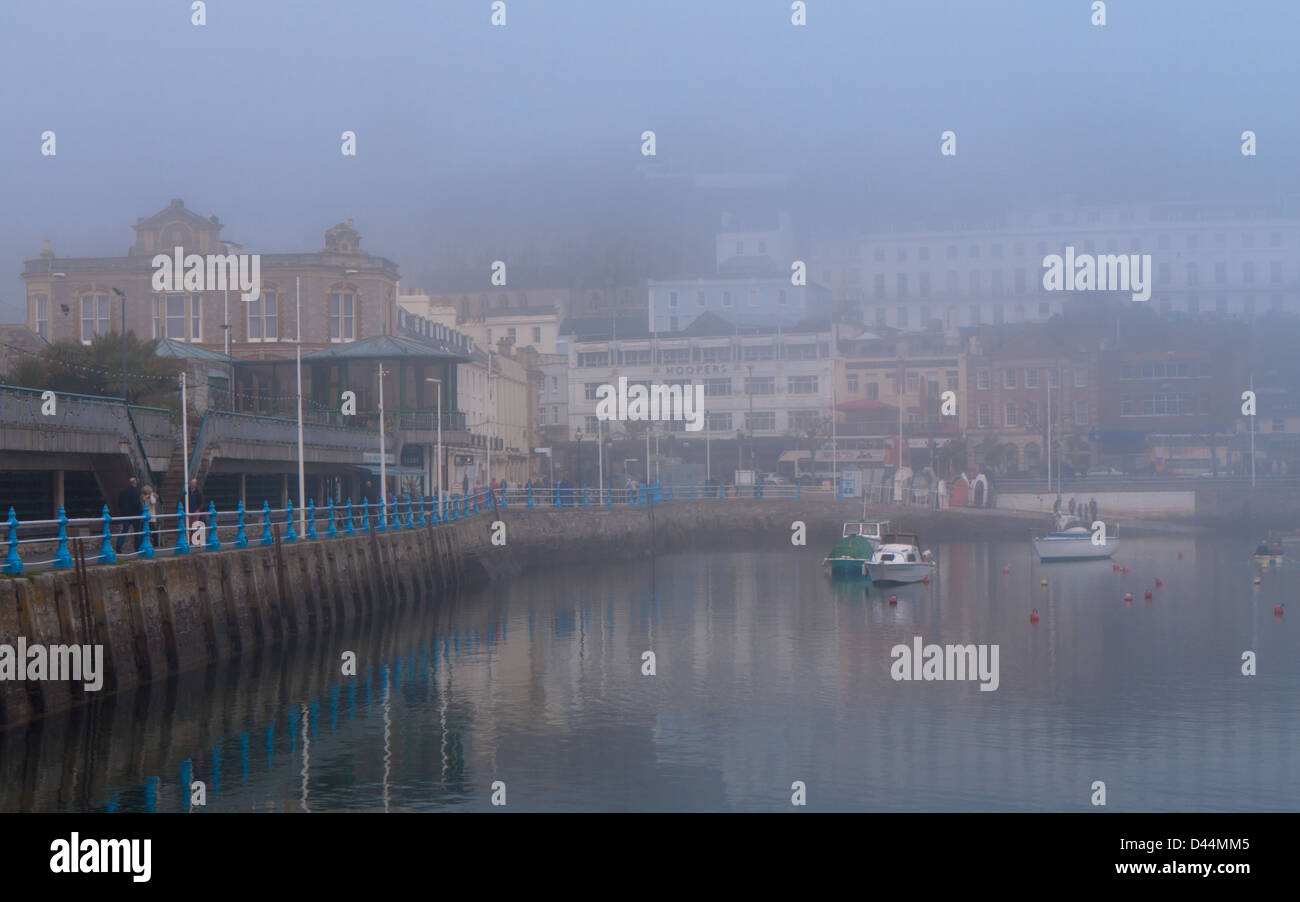 Vue sur le port de Torquay sur un matin, encore, avec sea mist enveloppant les bâtiments. Banque D'Images