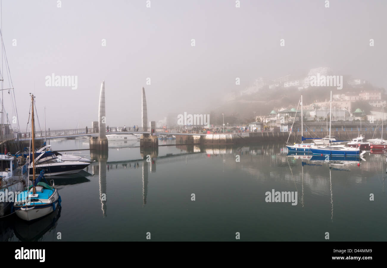 Vue sur le port de Torquay sur un matin, encore, avec sea mist enveloppant les bâtiments. Banque D'Images